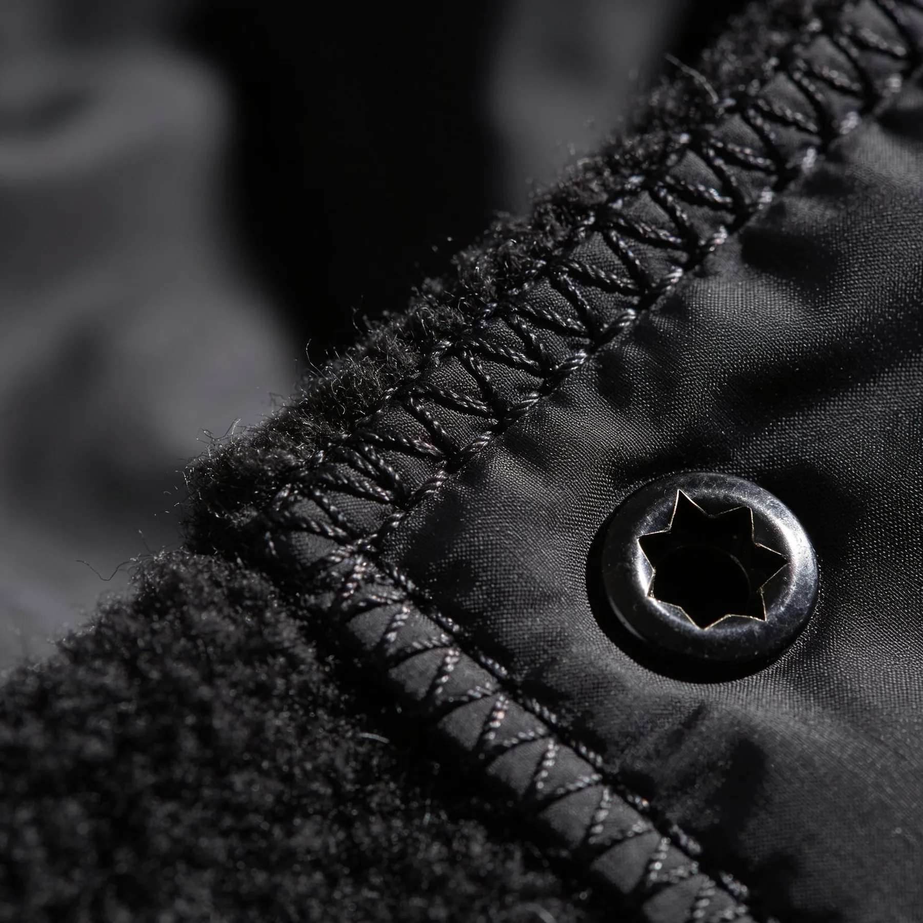 Macro detail of a raw boiled wool edge against coated nylon with heavy topstitching